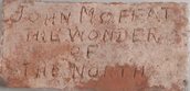 A simple brick, is inscribed with the words John Moffat, Wonder of the North