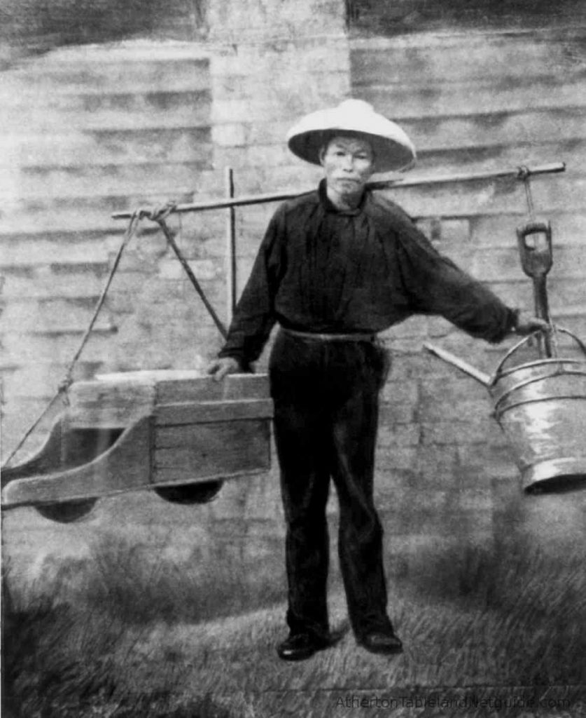 A Chinese gold miner carrying his tools on a yoke across his shoulders